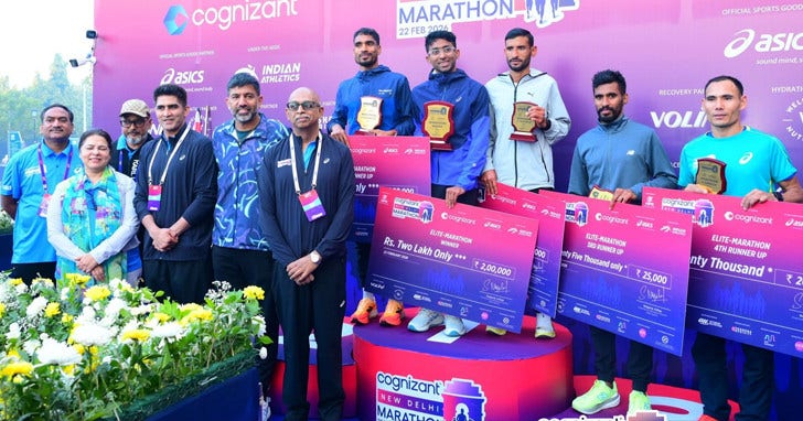 A group of marathon athletes on the podium holding the winning check