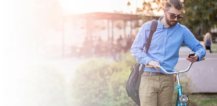 A man walking with a bicycle while watching something on his phone