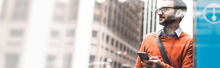Man holding smartphone while looking elsewhere