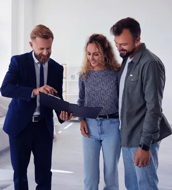 Three individuals stand in a room, examining a document