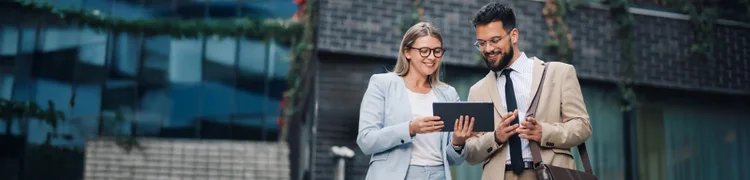 A man and woman are jointly holding a tablet, likely sharing ideas