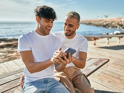 Individuals using mobile device on a beach.