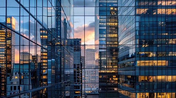 Modern glass buildings reflecting sunset light in dense urban cityscape