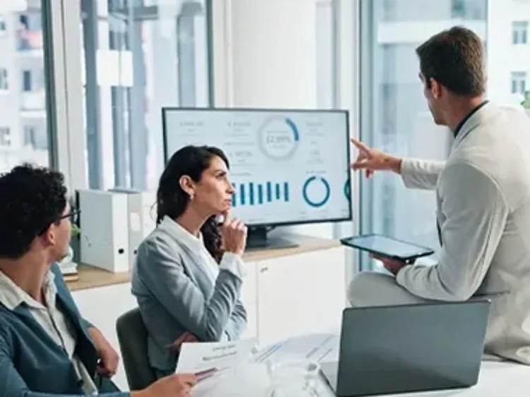 Team reviewing presentation data charts on monitor in modern office meeting