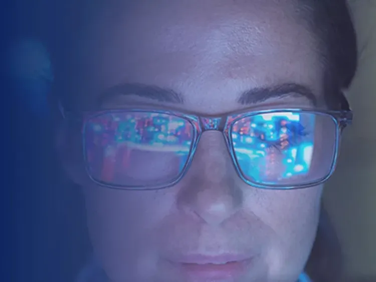 Close up of person wearing glasses with screen reflections visible