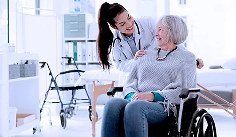 A doctor smiling and speaking to a lady in a wheelchair