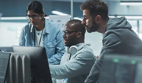 Three colleagues looking at a computer screen anxiously