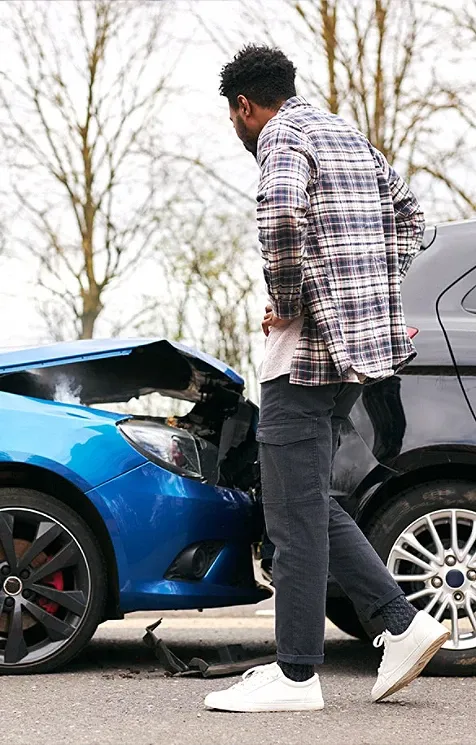 two crashed cars and someone looking at the damage