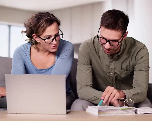 Couples reviewing financial papers with a laptop