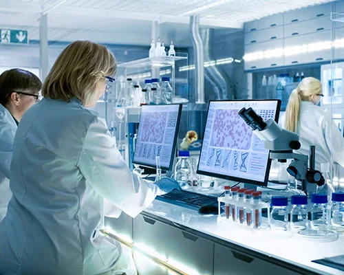 Technicians working with a microscope and monitors in laboratory