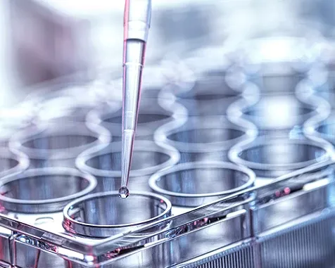 A close-up view of a dropper putting a liquid in a test tube.