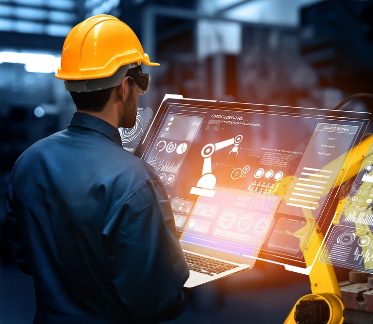 Man looking at a monitor which has robot arms