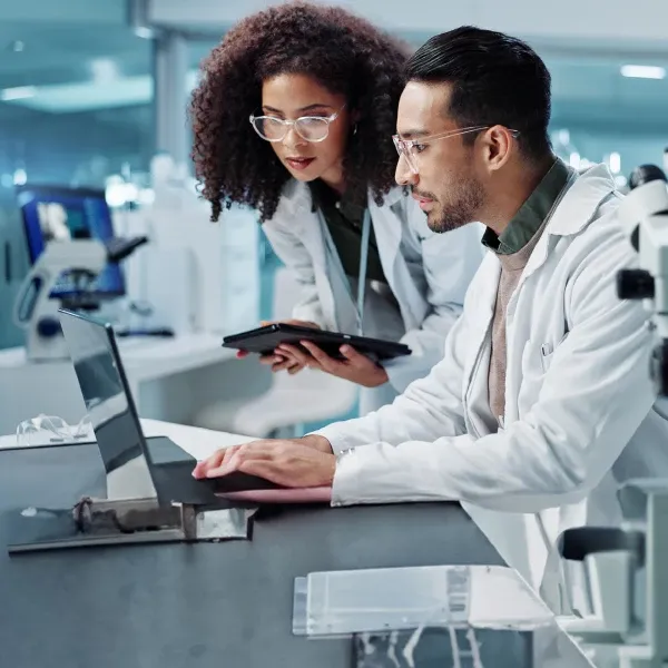 two life healthcare lab technicians looking at a laptop screen