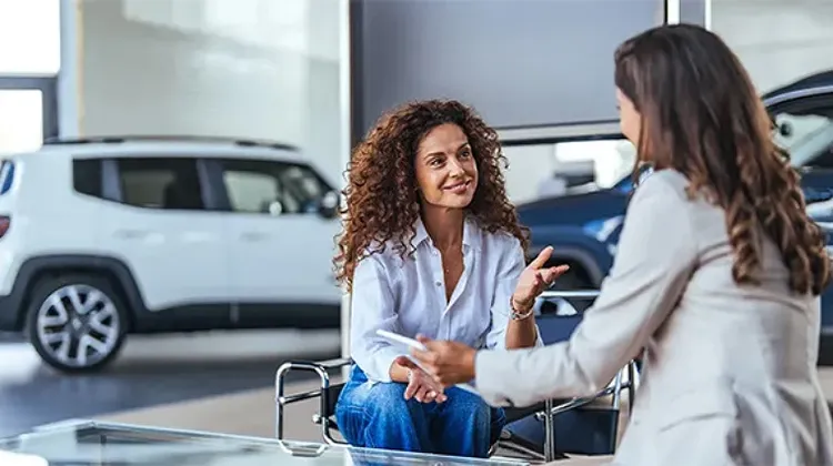 Two professionals discussing details inside an automotive showroom