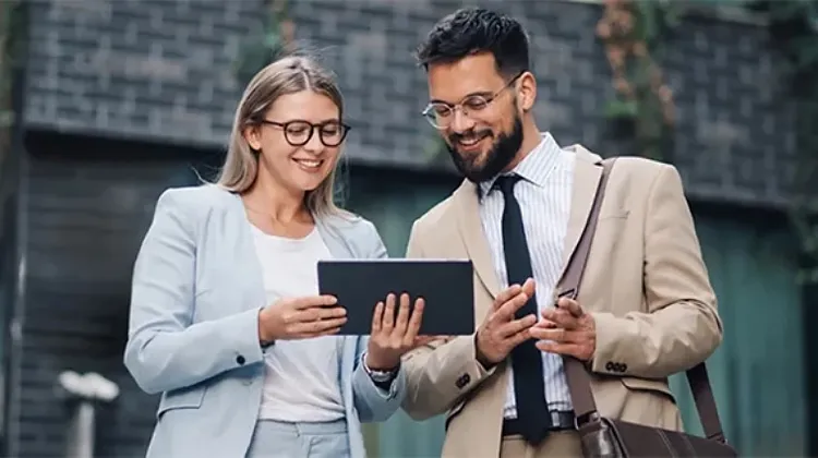 Two professionals reviewing information on a tablet outdoors