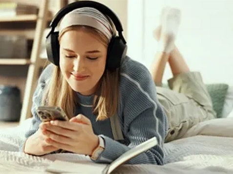 A woman lying on a bed checking her phone