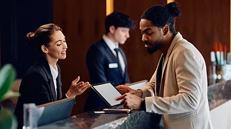 African American man checking in at reception desk in hotel.
