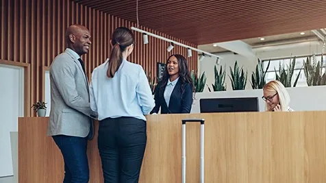 African American concierge checking in two smiling hotel guests