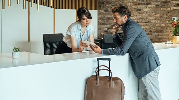 Businessman using digital tablet for checking in at hotel.