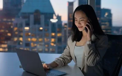 A female looking at a laptop at work while talking on the phone