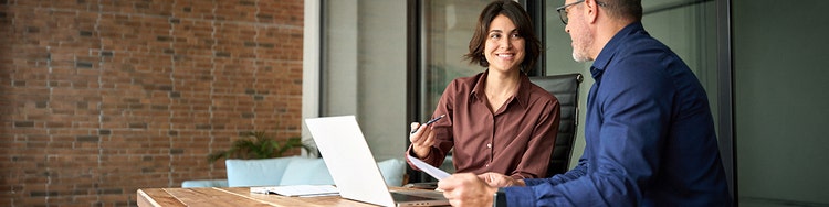Two professionals collaborating at a desk with a laptop.