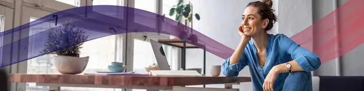 A woman is smiling while having a tea break in her workspace.