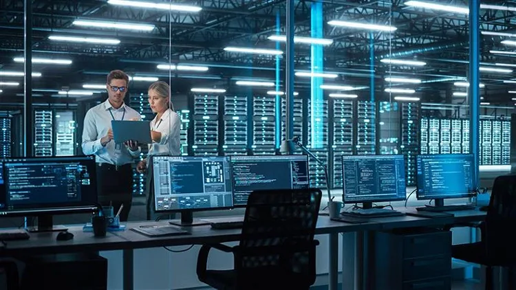 A male and female colleague looking at computer screen in a data center room.