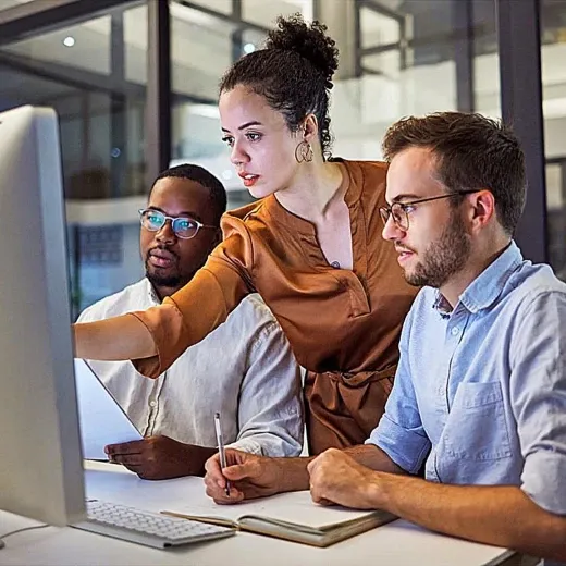 Three people looking at a desktop computer