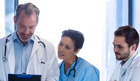 Three people standing next to each other looking at a tablet