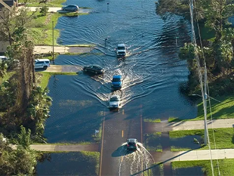 Aerial view of evacuating cars and surrounded with water houses in suburban residential area