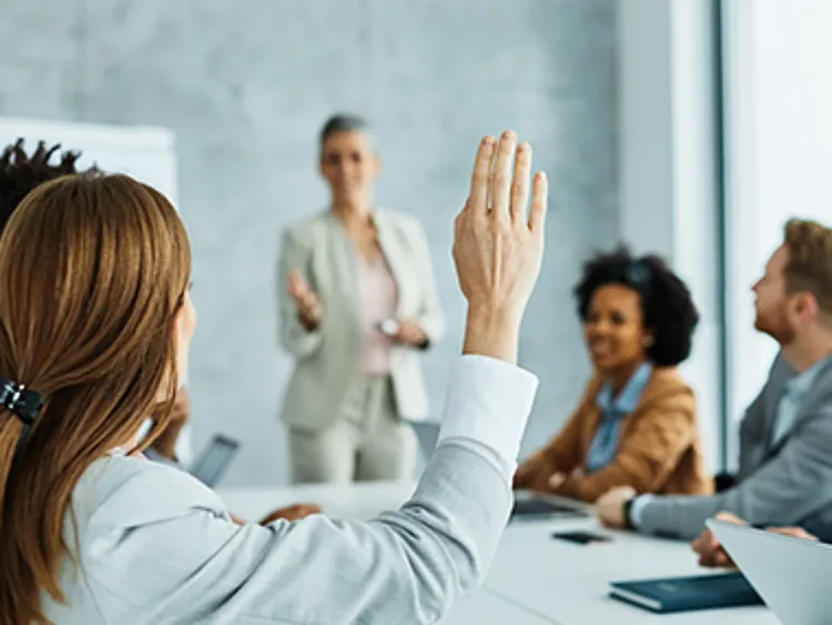 A woman with raised hand in a business meeting