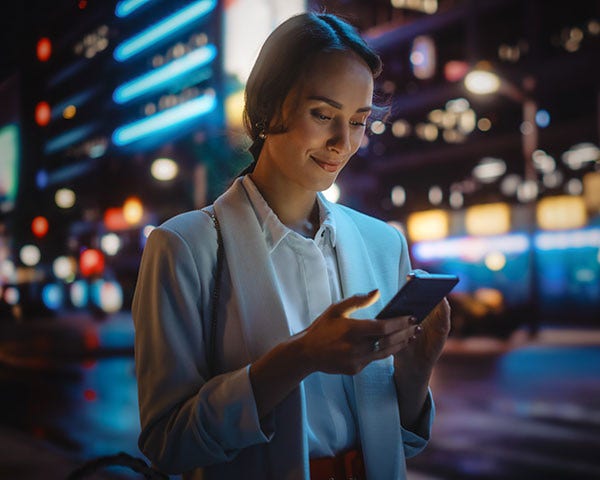 A woman using mobile phone on street night time