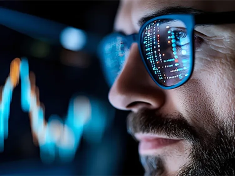 Close-up shot of a man wearing specs that reflect a digital screen