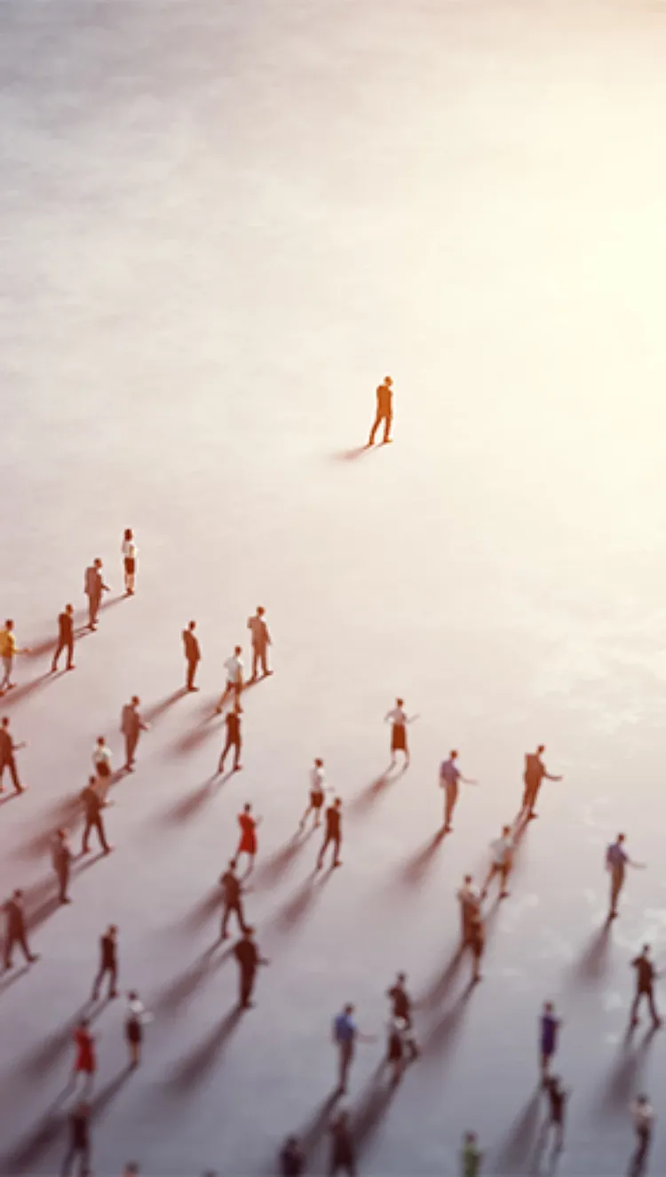 Arial view of one person walking ahead of a large group of people, towards a bright light.