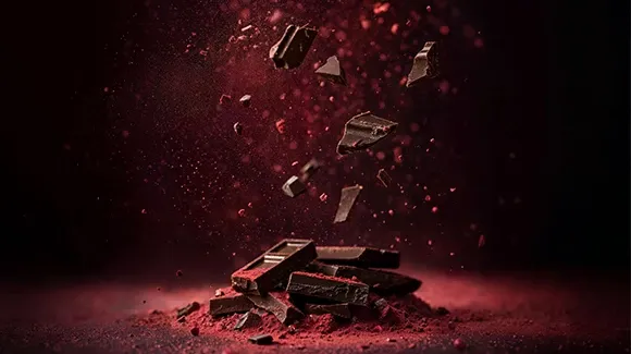 Dark chocolate pieces breaking apart in midair, highlighting premium cocoa ingredients and chocolate production.